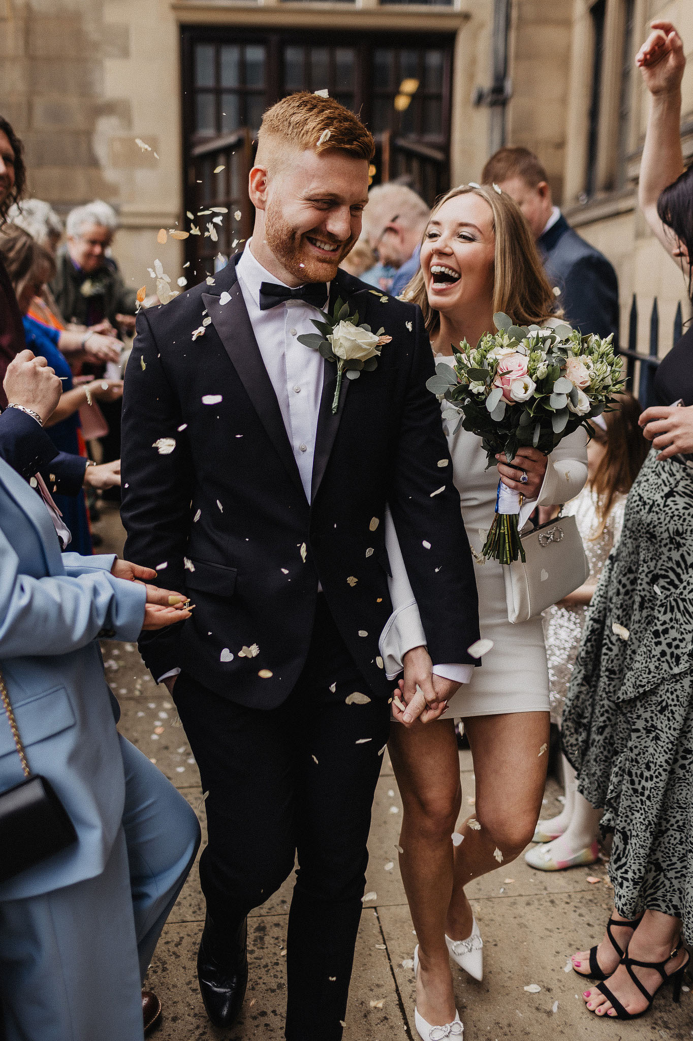 Joyful newlyweds with confetti exit celebration.